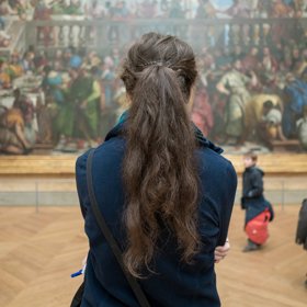 Turistka pozoruje obraz Svatba v Káně, který visí přímo naproti slavné Moně Lise (Paříž, Francie).