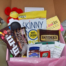 Menstruační krabička první pomoci obsahuje čokoládové tyčinky, popcorn, celozrnné drobnosti, plyšového medvídka s nápisem „Jsi perfektní“ nebo bombičku do koupele.