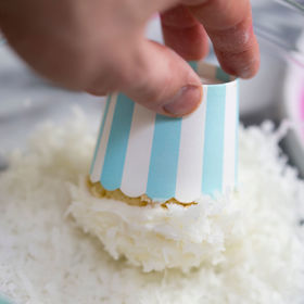 Muffin uchopíme do ruky za košíček a krém „namočíme“ do strouhaného kokosu.