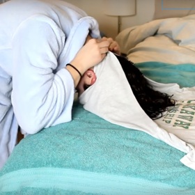 5. Uchopíme cípy trika u spodního lemu a spojíme je v zátylku.