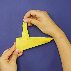 3. Takto složený ubrousek přeložíme podél svislé osy, uchopíme ho za růžky jednou rukou, natočíme si ho dle obrázku a druhou rukou vytahujeme z ubrousku vrstvu po vrstvě.