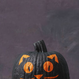 2. Čarodějčin kocour. Z malířské lepicí pásky vystřihněte ouška, oči, čumáček a vousky a nalepte je na dýni. Přestříkejte ji černou akrylovou barvou, nechte zaschnout a pásku odlepte.