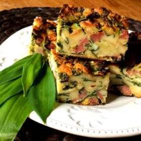 Nádivka s medvědím česnekem

Suroviny:

obyčejné rohlíky (den staré) 8 ks
mléko asi 2 dl
cibule 2 ks
jarní cibulka 2 ks
uzené maso 400 g
vinná klobása 150 g
vejce natvrdo 3 ks
čerstvý medvědí česnek 2 velké hrsti
baby špenát 2 velké hrsti
mandle (plátky, hranolky nebo nahrubo nasekané) 80 g
vejce 6 ks
kypřicí prášek 1/2 sáčku
muškátový oříšek
sůl a čerstvě namletý pepř
máslo na vymazání formy

Postup:

Rohlíky nakrájejte na menší kostičky o hraně asi 1,5–2 cm a dejte je do velké mísy. Zalijte je mlékem a promíchejte. Rohlíky by neměly být úplně namočené, spíš jen lehce zvlhlé.
Na pánvi rozehřejte trochu másla a orestujte na něm dosklovata nahrubo nakrájenou cibuli a jarní cibulku, poté přidejte na centimetrové kostičky nakrájené uzené maso a chvíli opékejte, potom vypněte oheň a směs nechte chladnout.
K rohlíkům vymačkejte ze střívka syrovou vinnou klobásu, přidejte na kostky nakrájená vařená vejce a nasekaný medvědí česnek a špenát. Také vmíchejte oloupané a nasekané mandle.
V menší misce lehce rozšlehejte syrová vajíčka, přidejte asi 1–2 lžičky soli, čerstvě namletý pepř a nastrouhaný muškátový oříšek. Poté zašlehejte kypřicí prášek. Vaječnou směs vlijte do velké mísy k rohlíkům, lehce promíchejte a pak pořádně promíchejte rukama, aby se směs dobře spojila.
Zapékací mísu vymažte máslem a rovnoměrně na ni naneste nádivkovou směs, nemusíte ji moc pěchovat, jen lehce zarovnat. Pečte v horkovzdušné troubě vyhřáté na 180 stupňů 40–45 minut, až bude povrch hezky opečený. Nádivku nechte před servírováním lehce zchladnout, aby se zpevnila.