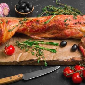 Středozemní králík na rozmarýnu, rajčatech a olivách.