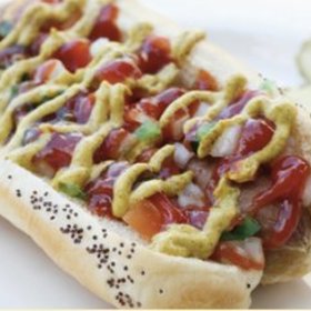 Debrecínský hot dog

Proříznutou celozrnnou bagetku můžeme mírně nahřát v troubě. Poctivou selskou slaninu nakrájíme na proužky a opečeme na pánvi dokřupava. Poctivý debrecínský párek ohřejeme, případně můžeme opéct na pánvičce či grilu. Do pečiva vložíme párek, zakápneme hořčicí, posypeme nakrájeným čínským zelím, cibulkou a křupavou slaninou.