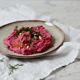 Hummus z červené řepy:

Suroviny:

250 g sušené cizrny
1 větší vařená červená řepa
50 ml vody z uvařené cizrny
200 ml olivového oleje
3 lžičky tahini
šťáva z 1 citronu
1 šalotka
2 stroužky česneku
½ chilli papričky
2 lžičky mletého římského kmínu
sůl, pepř.

Postup:

Cizrnu naložte do vlažné vody na 6 až 8 hodin nebo přes noc, aby zvětšila svůj objem. Vodu z cizrny slijte a pro samotné vaření použijte novou. Vařte 1–1,5 hodiny do změknutí a nechte vychladnout.

Cizrnu vložte do stolního mixéru spolu se solí, olivovým olejem, červenou řepou nakrájenou na menší kousky a 50 ml vody z cizrny mixujte alespoň 10 minut.

Přidejte tahini, šťávu z jednoho citronu a dále mixujte.

Šalotku spolu česnekem zbavte slupky a vše přidejte do mixéru. Hummus dochuťte římským kmínem, chilli papričkou a pepřem. Vše spolu mixujte dalších 5-10 minut, dokud nebude hummus hladký.

Hotový hummus podávejte s čerstvě nakrájeným koprem a nasekanými mandlemi.