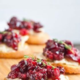 Jednohubky s brusinkami:

Suroviny:

5 plátků tmavého toastového chleba, 120 g hermelínu, 3 lžíce zavařených brusinek, 1 malou chilli papričku, 3 lžíce smetany, dvě hrsti rukoly, párátka.

Postup:

Každý plátek chleba rozdělte na 4 stejné čtverce a dejte je nasucho opékat na pánev nebo do trouby. Do vyšší nádoby dejte brusinky, smetanu a chilli papričku a pomocí ponorného mixéru vytvořte hladkou omáčku. Každý opečený čtvereček potřete omáčkou, přidejte pár lístků rukoly, kousek hermelínu a vše upevněte párátkem.