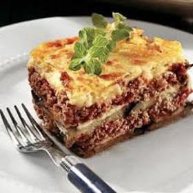 Musaka s lilkem:

Suroviny:

olivový olej 6 lžic,
menší cibule, na kostičky 2 ks,
mleté jehněčí nebo hovězí maso 300 g,
špetka mleté skořice,
špetka drceného římského kmínu,
sušené oregano 2 lžičky,
česnek na plátky 3 stroužky,
konzervovaná rajčata 1 plechovka (400 g),
červené víno,
sůl a čerstvě namletý pepř,
menší lilky 2 ks,
brambory 5–6 ks,
máslo 2 lžíce,
hladká mouka 2 lžíce,
mléko asi 100 ml,
smetana ke šlehání (33 % tuku) 100 ml,
špetka mletého muškátového oříšku,
parmazán 30 g,
bílý chléb k podávání, lze vynechat.

Postup:

Na 5 lžících oleje opečte nadrobno nakrájenou cibuli dozlatova, přidejte maso a opečte ho několik minut ze všech stran a přidejte koření a prolisovaný česnek. Míchejte a krátce opékejte, aby se koření rozvonělo a česnek se nepřichytil. Nakonec přidejte rajčata, osolte, opepřete, promíchejte a podlijte vínem. Přiklopte poklicí a nechte na mírném plameni cca půl hodiny probublávat. Občas zkontrolujte, zda se směs nepřipaluje, když tak podlijte ještě troškou vína.
Mezitím rozpalte troubu na 180 °C. Nakrájejte na cca centimetrové plátky omyté lilky, osolte je a dejte na plech na pečicí papír cca na 20 minut péct do trouby. Zatímco se pečou lilky, oškrábejte brambory a také je nakrájejte na plátky (tenčí, cca 3 mm).
Do zapékací misky vytřené zbylým olivovým olejem narovnejte vrstvu brambor, osolte je, na ně dejte vrstvu masové směsi a tu poklaďte plátky lilků. Vrstvy opakujte, dokud máte materiál (záleží to i na velikosti vaší zapékací misky). Horní vrstva by měly být brambory. Dejte péct přikryté poklicí nebo alobalem na 45 minut do trouby rozehřáté na 150 °C (horkovzduch) nebo 170 °C.
V kastrůlku rozehřejte 2 lžíce másla, opečte na nich mouku na velmi světlou jíšku, tu pak zalijte studeným mlékem a smetanou, ochuťte oříškem a nechte projít varem. Přidejte sýr, lehce promíchejte, než se rozpustí. Bešamel má být docela řídký, aby se dal nalít na musaku. Pokud ho máte hustý, nařeďte ho mlékem.
Po 45 minutách pečení musaku zalijte bešamelem a dejte do trouby na dalších cca 20 minut, teplotu zvedněte na 180 °C (pokud používáte horkovzduch), jinak na 200 °C. Pečte už odkryté. Výsledkem by měla být pěkně zlatavá vrstva na povrchu. Po upečení nechte ještě minimálně pět minut odpočívat, aby se musaka dala lépe krájet.