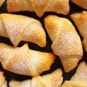 Hrníčkové rohlíčky

Suroviny:

Na těsto

5  hrnek hladká mouka
1,5  hrnek mléko vlažné
1  kostka droždí 42g
200  g rostlinný tuk
1  ks vejce
1  lžička sůl
1  špetka cukr

Na náplň: 1)

1  ks pórek střední
100  g tvrdý sýr 80 - 100
150  g uzeniny anglická slanina, šunkový salám, libový párek apod.
1  ks vejce

2)
250  g tvrdý sýr
1  ks vejce
3  stroužek česnek 2 - 3
Na dokončení zbylého:
1  ks vejce na potření
sůl hrubá
česnek sušený
kmín

Postup:

Těsto:

Do mísy prosijeme mouku. V prostředku uděláme důlek, nalijeme trochu vlažného mléka, přisypeme cukr a rozdrobíne droždí. Takto připravený kvásek necháme vzejít, pak smícháme s moukou, rozpuštěným tukem (nejvíce se mi osvědčilo dělat z másla a sádla půl na půl, ale lze použít i Heru), vejcem, zbylým mlékem, solí a vypracujeme tužší těsto, které necháme 45 minut kynout.

Příprava náplní: 

1) pórek rozřízneme podélce, umyjeme a příčně nakrájíme na co nejjemnější půlkolečka. Uzeninu nakrájíme na malé kostičky a sýr nastrouháme na středním struhadle. Pokud chcete, můžete okořenit oregánem. Vlijeme půlku rozšlehaného vajíčka (spolu se sýrem funguje jako pojidlo, aby se vám náplň při jezení nesypala ven).

2) sýr nastrouháme na jemném struhadle, přidáme syrové vejce a rozetřený česnek. Většinou není třeba solit - sýr bývá dost slaný.

Těsto rozdělíme na šest až osm částí (záleží, jak velké rohlíčky chceme dělat) a z poloviny těchto částí děláme pórkovo - uzeninové rohlíčky: Každou část postupně na pomoučeném vále vyválíme do kruhu s tloušťkou asi 4 mm. Překrojíme napříč na osm dílků ve tvaru trojúhelníku. Naplníme mírně náplní a srolujeme od širšího konce do tvaru rohlíčku. Konec (špička) těsta by měla být pod rohlíkčm dole, aby se při kynutí a pečení nerozmotal. Rohlíčky necháme ještě 10 minut kynout a poté potřeme rozšlehaným vajíčkem, můžeme posypat hrubou solí, oreganem nebo i kmínem a pečeme ve středně vyhřáté troubě cca 15 minut.

Z druhé poloviny těsta (tedy zbylých 3 - 4 částí) děláme sýrovo-česnekové pletýnky: Každou část rozdělíme na 8 dílků, každý rozválíme do dlouhého pruhu, který podélně potřeme ve středu hmotou ze strouhaného sýra, vajíčka a česneku. Pak pruh smotáme jako roládku, aby náplň byla uvnitř a z této plněné "nudle" uvážeme preclík. Opět necháme ještě 10 minut kynout, potřeme vejcem a můžeme posypat hrubou solí, granulovaným česnekem a pod.

Pečeme také ve střední troubě 15 minut.