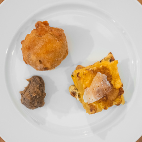 Kroketa z uzeného kuřete se salsou z morku:
Suroviny:
• 1 uzené bio kuře
• 150 g hladké bio mouky
• 1 l plnotučného bio mléka
• na špičku nože strouhaný muškátový oříšek
• 100 g bio másla
• 2 bio vejce
• strouhanka
• 1 l bio oleje na smažení
• 3 bio morkové kosti rozříznuté podél
• 1 zelená bio paprika
• 3 stroužky česneku
• 1 chilli paprička.
Postup:
Uzené kuře vykostíme. Obrané maso nakrájíme na malé kostky a skelet s kůží dáme pomalu ohřívat do mléka (mléko nemá vřít, jen se hřát). Necháme takto "táhnout" asi tři hodiny, potom mléko scedíme a necháme vychladnout.
Na pánvi rozehřejeme máslo a přidáme mouku. Za stálého míchání opražíme mouku, dokud se nevytratí "moučná" vůně, a přilijeme studené mléko z uzeného kuřete. Přidáme na špičku nože strouhaného muškátového oříšku a šleháme metlou. Vzniká hustý bešamel, který necháme krátce a za stálého šlehání provařit. Bešamelem spojíme nakrájené kostky uzeného kuřecího masa a necháme vychladnout.
Ze studené hmoty formujeme krokety o velikosti většího ořechu a postupně obalujeme v mouce, rozšlehaných vejcích a prosáté strouhance. Krokety smažíme ve vyšší vrstvě rozehřátého oleje dozlatova a necháme okapat na papírovém ručníku.
Morkové kosti, papriku, chilli a česnek upečeme na grilu nebo v troubě (250-280 °C) dozlatova. Papriku oloupeme a pečený morek s paprikou, chilli a česnekem dáme do mixéru a důkladně rozmixujeme. Podle chuti osolíme a podáváme s kroketami.