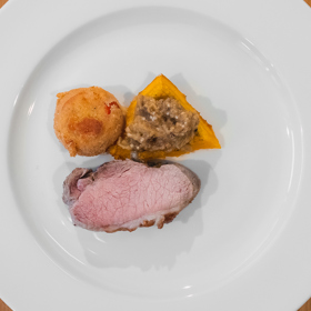 Vepřové karé na páře, smažené rajče a pečená dýně s lilkem:
Suroviny:
400 g bio vepřového karé (bio vepřová pečeně bez kosti)
2 tvrdší bio rajčata
2 bio vejce
100 g hladké bio mouky
100 g prosáté strouhanky z bílého pečiva
0,5 l bio řepkového oleje na smažení
1 máslová bio dýně
2 bio lilky
1 stroužek česneku
sůl
pepř
vinný ocet
panenský olivový bio olej.
Postup:
Vepřové karé zbavíme blány, důkladně osolíme, opepříme a polijeme vinným octem, zabalíme do alobalu nebo potravinové fólie a necháme alespoň hodinu odpočinout.
Pokud máme k dispozici parní troubu nebo konvektomat, nastavíme režim páry 65 °C na cca 3 hodiny.
Pokud nemáme k dispozici parní troubu, použijeme alobal a dáme karé do trouby na 80 °C na cca dvě
hodiny.
Pod grilem v troubě necháme péct lilky a dýni. Máme-li k dispozici gril, necháme na něm zeleninu ze
všech stran spálit, dokud není zcela měkká. (Lilek je hotový poměrně rychle, dýně trvá mnohem déle.)
Vydlabeme upečenou dužinu dýně a ochutíme solí, olivovým olejem a kapkou vinného octa. Taktéž
vydlabeme upečenou dužinu lilku, rozmačkáme vidličkou a ochutíme utřeným česnekem, solí, olivovým
olejem a kapkou vinného octa.
Z rajčete odřízneme "čepičku", spodek a vršek a rozpůlíme ho. Tak získáme dva silnější řízky rajčete a
obalíme v mouce, našlehaných vejcích a prosáté strouhance a osmažíme v rozehřátém řepkovém oleji dozlatova.
Podáváme předvařené a ze všech stran opečené vepřové karé nakrájené na plátky, pyré z dýně a lilku a smažené rajče.