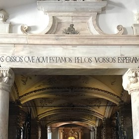 Morbidní nápis na portálu kaple v překladu znamená: My kosti zde přítomné, čekáme na ty Vaše.