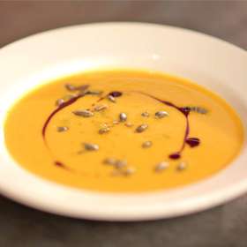 Dýňová polévka s praženými dýňovými semínky a dýňovým 
olejem:

Suroviny:

50 g		olivový olej
80 g		 cibule
20 g		zázvor
60 g 		cukr krupice
500 g 		dýně očištěná
120 g 		pomerančová šťáva
600 g		zeleninový vývar
sůl
25 g 		citron
50 g		smetana 33%

20 g		dýňový olej
60 g		dýňová semínka
60 g		kmínový chléb
olej na smažení
pažitka.


Postup:

V kastrolu na olivovém oleji zpěňte na kostičky nakrájenou cibuli, přidejte zázvor na kostičky, cukr a nechte ho lehce zkaramelizovat. Přidejte dýni nakrájenou na kostičky a krátce ji orestujte. Pak přidejte pomerančovou šťávu a do půlky ji vyvařte. Nakonec přidejte zeleninový vývar a pomalu vařte do změknutí. Jakmile je dýně měkká, tak přidejte smetanu a krátce povařte. Pak rozmixujte, propasírujte přes jemný cedník a dochuťte solí a citronovou šťávou.

Dýňová semínka opražte v troubě nebo na suché pánvi dokřupava. Kmínový chléb nakrájejte na malé kostičky a usmažte je v horkém oleji dozlatova a hned dejte na savý papír usušit od přebytečného tuku. Pažitku jemně nakrájejte.
