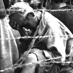 Váleční zajatci za ostnatým drátem v japonském vězeňském táboře v roce 1945. 