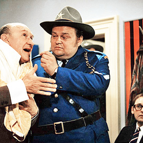 Neschopná policie – strážník Brooks (Jan Libíček) a komisař Sheridan (František Filipovský) – z vražd nejprve obviní učitele Camela.