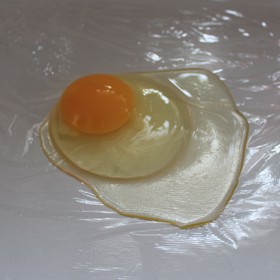 Z potravinářské fólie si nastříhejte čtverce, které můžete slabě pomazat olejem.  Na ně vyklepněte vejce, ideálně z co nejmenší vzdálenosti, aby se nesmísil žloutek s bílkem. 