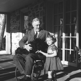 Franklin D. Roosevelt a Ruthie Bie, dcera prezidentových známých, se mazlí s Rooseveltovým pejskem jménem Fala.