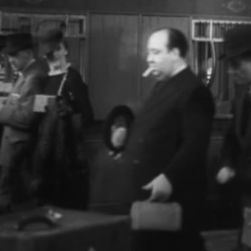 Alfred Hitchcock se často objevoval ve svých filmech, i když jen v miniaturních rolích. Tady jako jeden z lidí procházejících nádražím ve snímku Zmizení staré dámy (1938).