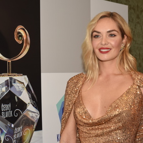 Na letošním vyhlašování pěveckých cen Zlatý slavík zazářila Taťána ve výrazné zlaté róbě. Dobře ví, že k blyštivým a podobně pompézním šatům se hodí jednoduchý slušivý účes. Vlasy proto lehce zvlnila a dodala jim lehkou asymetrii, když jednu stranu zastrčila za ucho. „Prodat“ tak mohla třpytivou náušnici.
