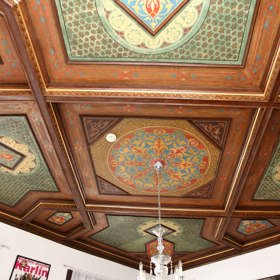 Dřevěný kazetový strop, který Jan Werich nechal zabetonovat před bolševiky, zdobí ředitelnu.