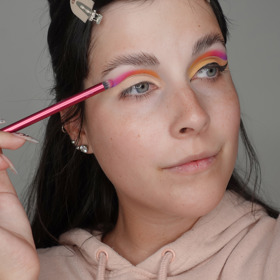 Na víčko naneste bázi pod oční stíny a následně začněte vedle sebe vrstvit barevné stíny od vnitřního koutku po vnější. Vždy je částečně překryjte přes sebe, aby vznikl hezký barevný přechod.