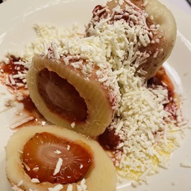 K jahodovým knedlíkům z tvarohového těsta se hodí strouhaný tvrdý tvaroh a rozpuštěné máslo.