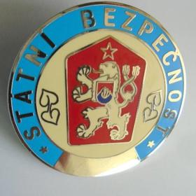 Odznak StB, kterým se mohli příslušníci této organizace prokazovat. V průměru měl čtyři centimetry. Na zadní straně byla sponka na připnutí. 