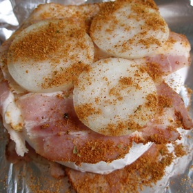 Labužnický grilovaný hermelín vytvoříme jednoduše. Na sýr navrstvíme anglickou slaninu, kolečka cibule a grilovací koření.