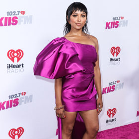 Herečka a zpěvačka Kat Graham v saténových fialových mini šatech na jedno rameno.