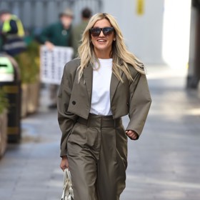 Ashley Roberts v khaki kalhotovém kompletu s cropped sakem, bílým tričkem, bílými lodičkami a bílou kabelkou do ruky.