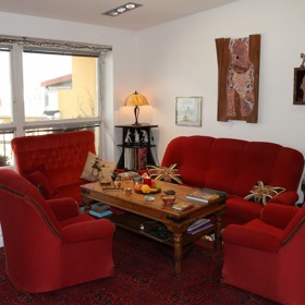 Dominantou obývacího pokoje je červená pohovka.