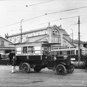 Autobus s řidičem a průvodčím první pražské autobusové linky před Vozovnou Centrála v Holešovicích. Snímek vznikl 9. května 1908. Dva měsíce poté, co v Praze začala fungovat první autobusová linka na trase Malá Strana - Hradčany.