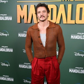 A jiný kardigan, tentokrát na prezentaci seriálu The Mandalorian. Tento síťovaný v barvě koňaku pochází z dílny Acne Studios (16 500 Kč). Pod ním měl Pedro šedé tílko Hanes (500 Kč) a outfit korunoval výrazně červenými kalhotami značky Acne Studios (10 300 Kč) a černými chelsea boots značky Adieu (10 500 Kč).