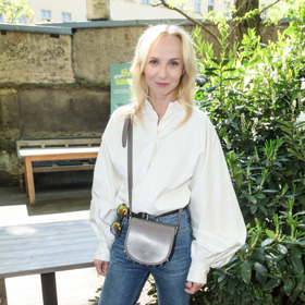 Plodková košili kombinuje s džínovými kalhotami a koženou crossbody kabelkou.