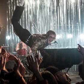 Rocketman je lehce fantazijní film, ale všechno vychází z toho, co se odehrávalo v hlavě Eltona Johna. Tahle "levitační" scéna se inspirovala fotografií pořízenou během jednoho koncertu, kdy se zpěvák opravdu odvázal. A někdy tehdy prý pochopil, že skutečně prorazil.