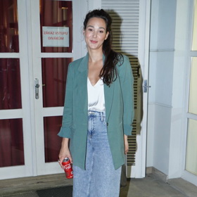 Herečka Vanda Chaloupková kombinuje delší sako v khaki barvě s širokými džínami a bílým topem.