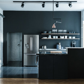 Díky prostupnosti světla působí i kuchyň s černou výmalbou uklidňujícím dojmem. Třešničkou na dortu je lampa s měděným detailem, na který odpovídá trup opřeného kola.