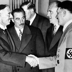 Britský premiér Neville Chamberlain si třese pravicí s Adolfem Hitlerem.