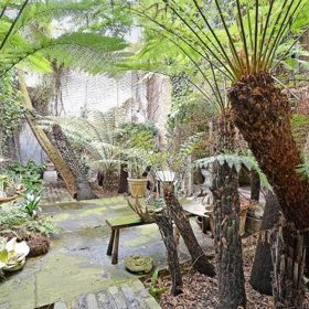 Zahrada ve vnitrobloku nezapře divokost. Roste v ní vše, co si v „zapomenutém“ stavení představíte – břečťan, popínavé rostliny nebo růže. A také palmy, které dělají zahradu, potažmo celý dům, ještě „podivnější“.