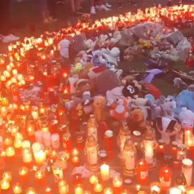 Lidé nosí před panelový dům svíčky a plyšáky.