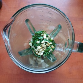 Nať vhoďte do mixéru. Oloupejte česnek a pokrájejte jej na menší kousky, přidejte posekané ořechy, olivový olej, citronovou šťávu, sůl a pepř. Mixujte, dokud nevznikne hladká směs.