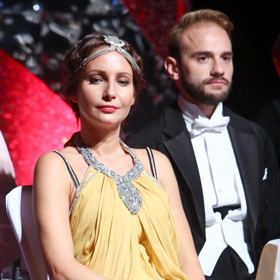 Herečka Veronika Arichteva má po vzoru 30. let rovněž ve vlasech výraznou bižuterii, kaštanové polodlouhé vlasy má lehce zvlněné a zatočené do kompaktního drdolu.