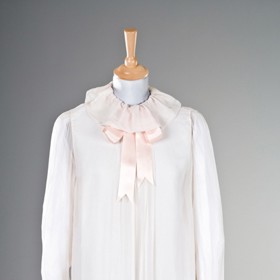 Dominantu romanticky narůžovělé krepové blůzy tvoří vázačka v oblasti krku.