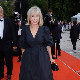 Jana Švandová má v  tyto nadýchané midi šaty s balonovými rukávy zjevně v oblibě. Známe je totiž už z filmového festivalu v Karlových Varech, kde je vynesla na červený koberec slavnostního zakončení v roce 2022. Tehdy k nim nazula nepřehlédnutelné balerínky Salvatore Ferragamo se zlatou přezkou, které patří k stěžejním kouskům jejího šatníku.