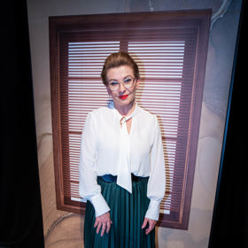 V tomto outfitu můžeme Danu Morávkovou vidět na pódiu - tmavě zelená plisovaná sukně a klasická bílá košile s vázankou.