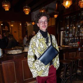 Herec Jan Cina oblékl na pražskou premiéru světle zelené sako s bílými květy, červené kalhoty s bílým proužkem a přes prsa ponechal svoji koženou tmavě modrou brašnu.