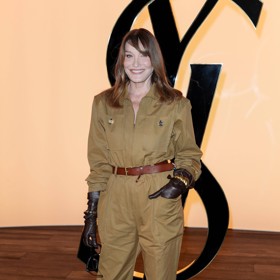 Bývalá francouzská první dáma Carla Bruni (56) rovněž dorazila v na přehlídku ve velmi šik outfitu - olivově zeleném overalu, výrazných hnědých kožených rukavicích a třešňově zbarvených lodičkách na moderním kotěcím podpatku.