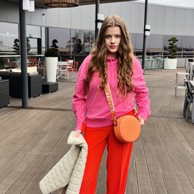 První dámský outfit inklinuje ke sportovně elegantnímu stylu. Vévodí mu výrazná oranžová a růžová barva.