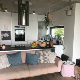 Kuchyni je laděná do bílé barvy, nad plotnou můžeme vidět designovou digestoř.