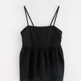 Do hledáčku lněných kousků na léto 2024 zařaďte i kratší topy. Černou blůzku s volánem najdete v Lindexu a stojí 599 Kč.